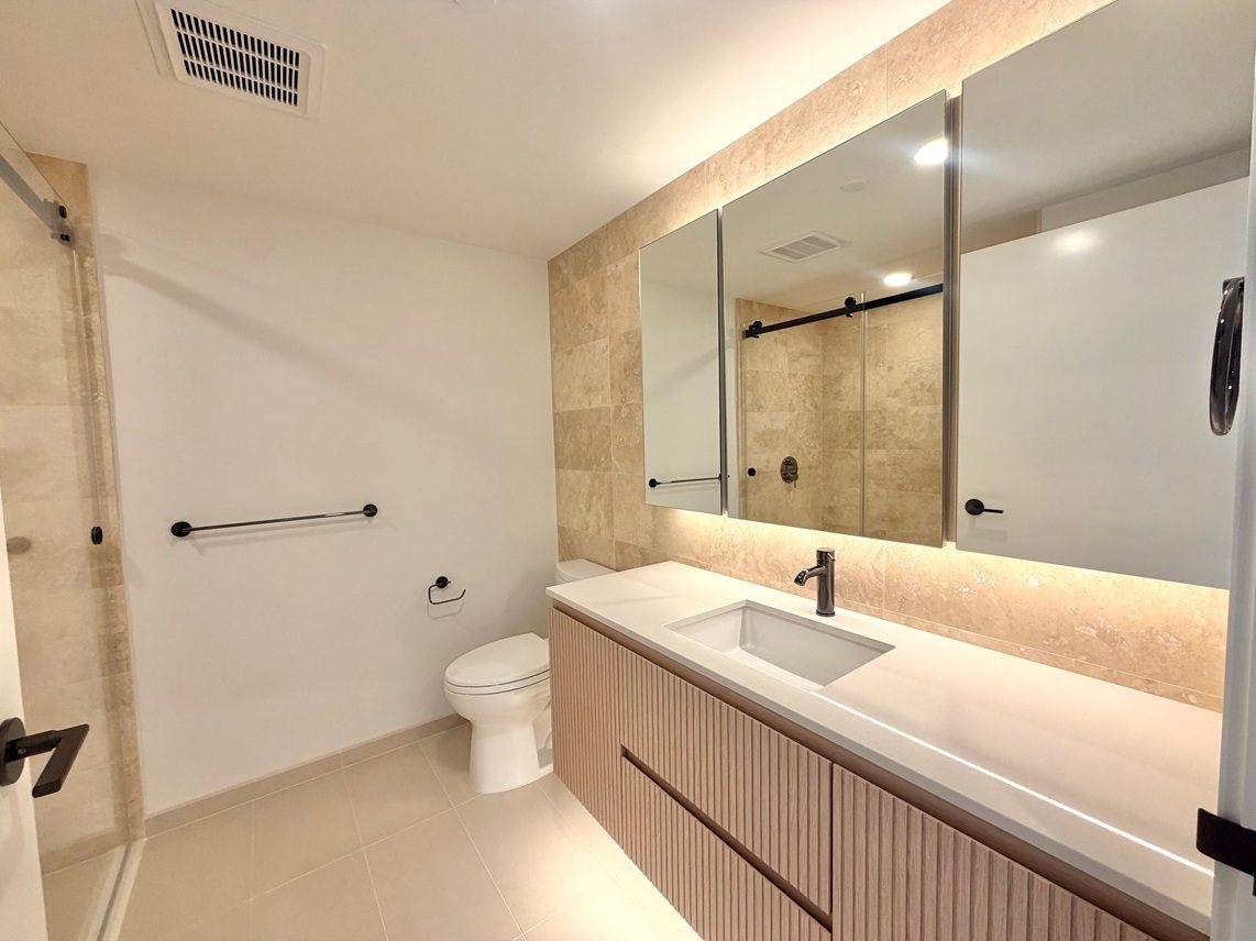 A bathroom with a toilet, sink, and a shower.